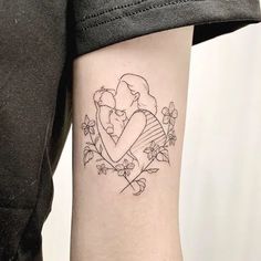 a woman's arm with a tattoo on it that has an image of a couple hugging