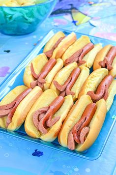 hotdogs with ketchup and mustard on buns in plastic containers sitting on a table