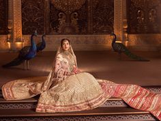 a woman sitting on top of a bench next to peacocks in an ornate room