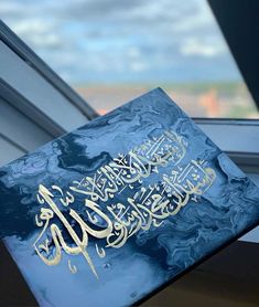 a blue book with arabic writing on it sitting in front of a window sill