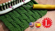 a close up of a toothbrush on top of a green knitted cloth with the letter l next to it