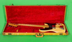 a yellow and black guitar in a case on a green background with red velvet lining