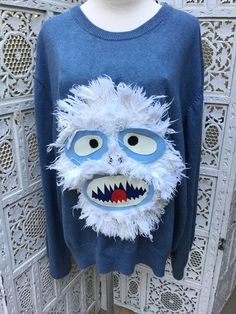 a blue sweater with an ugly monster face on it