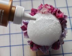 a close up of a bath ball on a tiled surface with a bottle of lotion next to it