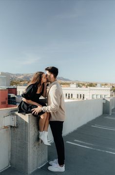 a man and woman kissing on top of a building