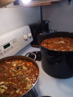 two pots of soup sitting on top of a stove