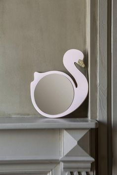 a white swan shaped mirror sitting on top of a shelf