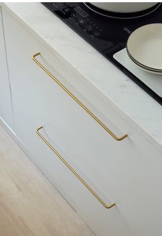 a white cabinet with gold handles on top of it next to a plate and bowl