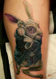 a rabbit with a pocket watch on its arm is shown in this tattoo art photo