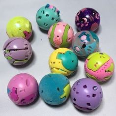 there are many different colored balls with holes in the top one is pink, blue, green, yellow and purple