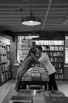 a man and woman kissing in front of a bookshelf filled with lots of books