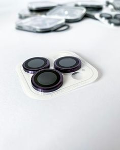 three black buttons sitting on top of a white surface next to scissors and eyeglasses