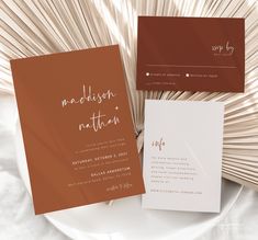 the wedding stationery is laid out on a white plate with an orange fan behind it