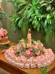 there is a cake decorated with pink flowers and greenery on the table next to it