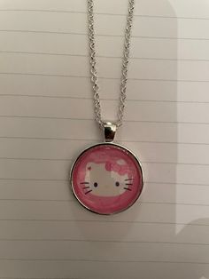 a hello kitty necklace is shown on a piece of paper with a chain attached to it