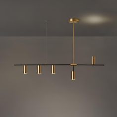 a modern light fixture hanging from the ceiling in a room with grey walls and flooring