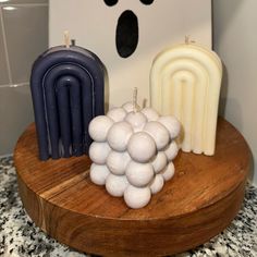 two candles are sitting on a wooden stand next to some soaps that look like grapes