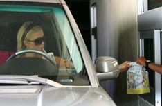 a woman in sunglasses driving a car and holding onto a bag with something on it