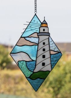 a stained glass lighthouse hanging from a chain