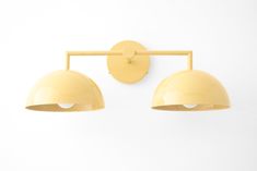 two yellow lights mounted on the side of a white wall next to each other,