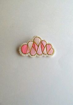 three pink and white embroidered brooches sitting on top of a white tablecloth