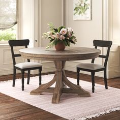 a dining room table with two chairs and a potted plant