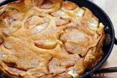 an apple pie in a cast iron skillet on top of a wooden table with utensils