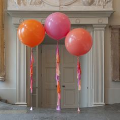 three balloons with tassels are in front of a doorway and statue on the wall