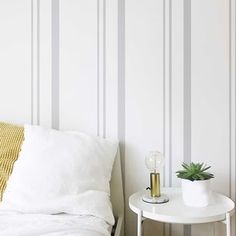 a white bed sitting next to a table with a potted plant on it