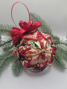 a christmas ornament with red ribbon and bow hanging from it's side