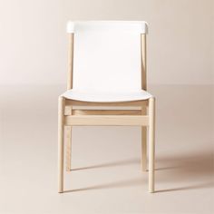 a wooden chair with white leather seat and back rests on a plain surface in front of a neutral background