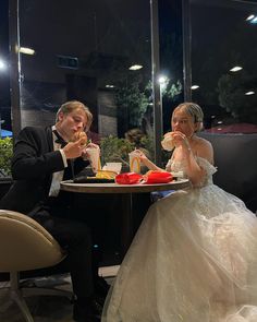 a man and woman sitting at a table with food in front of them on their wedding day