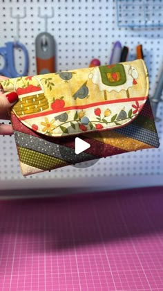 a person holding up a small wallet in front of a pegboard with scissors and other crafting supplies