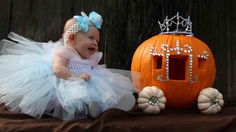 a baby sitting next to a pumpkin with a tiara