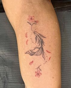 a woman's thigh with flowers and a bird tattoo on the side of her leg