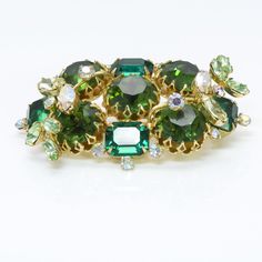 Hobe Green Crystal Brooch. Rare Hobé 1950’s brooch, gold tone with green crystals. Approximate Measurements: Length 2.6", Width 1.6" Made in: USA Condition: Very Good About The Designer Hobé jewelry is highly sought after by collectors of costume jewelry worldwide. The story begins with Hobé Cie, a fine jewelry line in France founded in 1887 by goldsmith Jacques Hobé in France. The costume jewelry division was added 40 years later by his son. Today, when costume jewelry collectors think of Hobé, Vintage Green Brooch For Evening, Vintage Green Brooch For Formal Occasion, Green Vintage Brooch For Formal Occasions, Vintage Green Brooches For Formal Occasions, Vintage Green Evening Brooches, Vintage Green Evening Brooch, Green Costume Jewelry Brooch For Collectors, Retro Green Brooch Jewelry, Vintage Green Brooch For Party