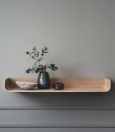 two vases with flowers are sitting on a shelf in front of a gray wall