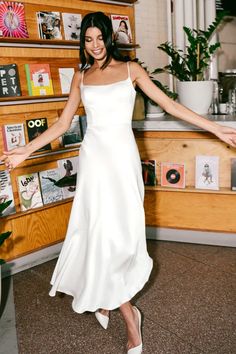 a woman in a white dress is posing for the camera with her arms spread out