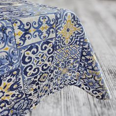 a blue and yellow table cloth on top of a wooden table covered in decorative designs