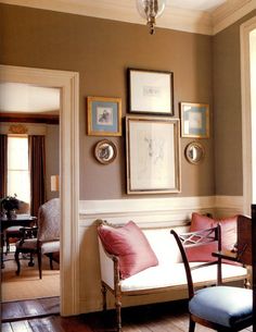 a living room filled with furniture and framed pictures on the wall above an open doorway