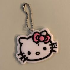 a hello kitty keychain with a pink bow on it's head hanging from a ball chain