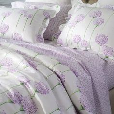 a bed with purple flowers on it and white sheets