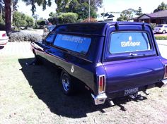 a purple pick up truck parked on top of a grass covered field