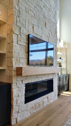 a large flat screen tv mounted to the side of a stone fireplace