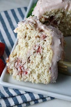 a piece of cake with frosting and strawberries on a plate next to a fork