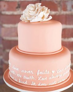 a pink wedding cake with white flowers on top and the words love is sweet written in cursive writing