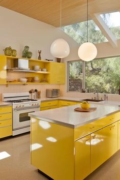 a kitchen with yellow cabinets and an island in front of the stove top ovens