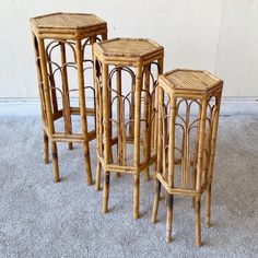 three small bamboo stools sitting next to each other on carpeted area with wall in background