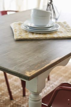 a wooden table with plates on top of it and a bowl sitting on top of the table