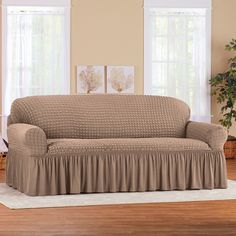 a living room with a couch covered in a brown cover and two windows behind it